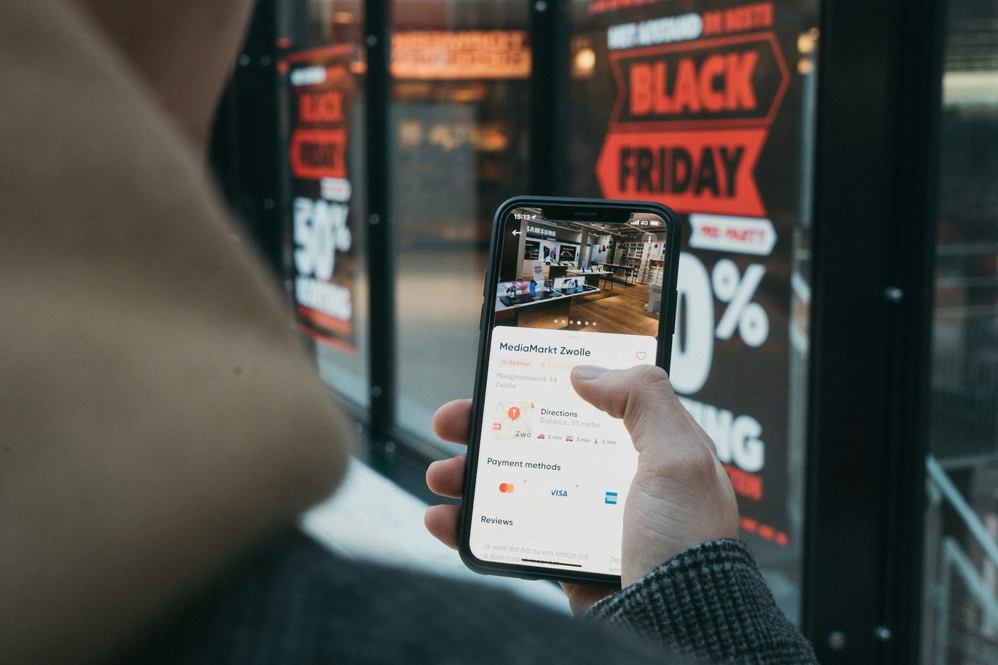 Téléphone affichant une boutique en ligne devant une vitrine en promotion