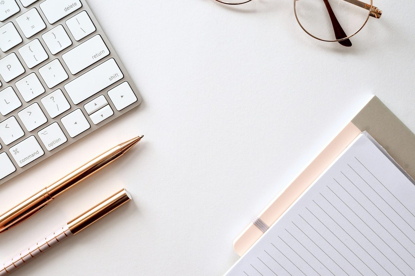 Carnet, stylo et clavier posés sur un bureau clair